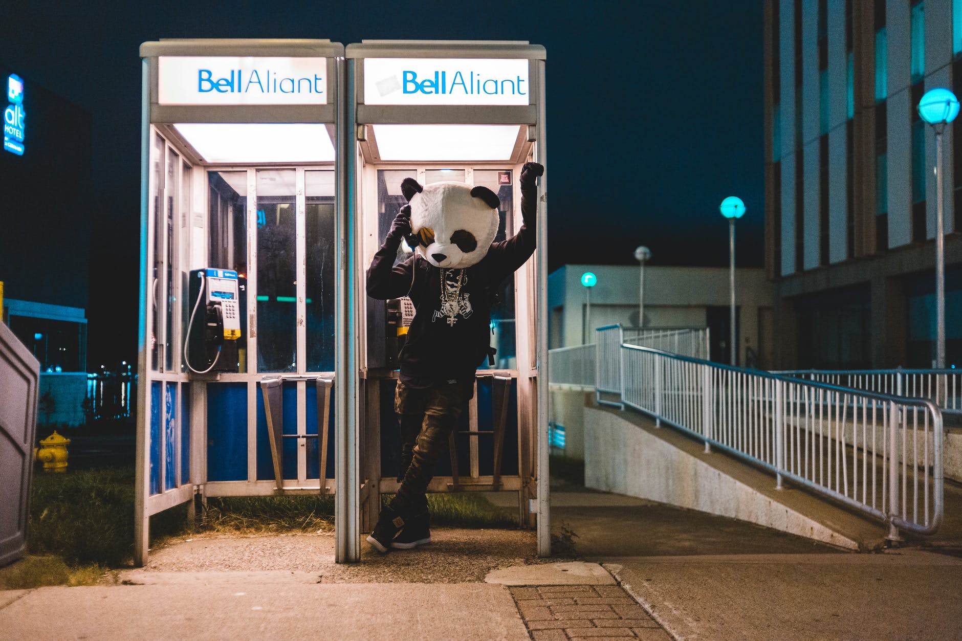 man in black and white panda costume standing on payphone booth during night time
